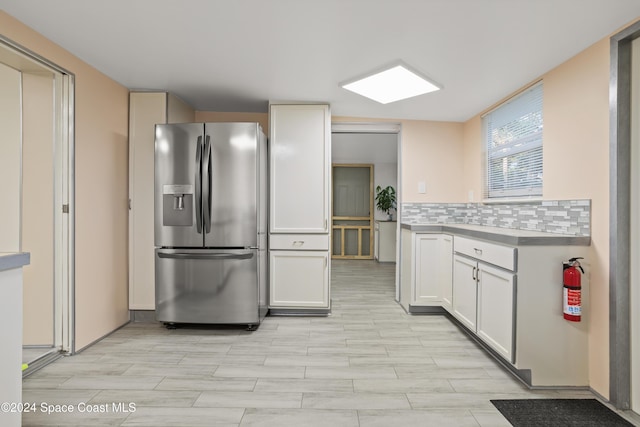 kitchen featuring white cabinetry, backsplash, and stainless steel fridge with ice dispenser