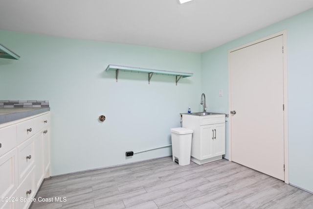 laundry room with cabinets, sink, and light hardwood / wood-style flooring