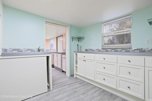 kitchen featuring white cabinets, decorative backsplash, and light hardwood / wood-style flooring