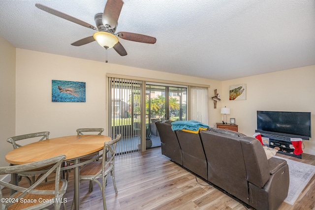 living room with ceiling fan, a textured ceiling, and light hardwood / wood-style flooring