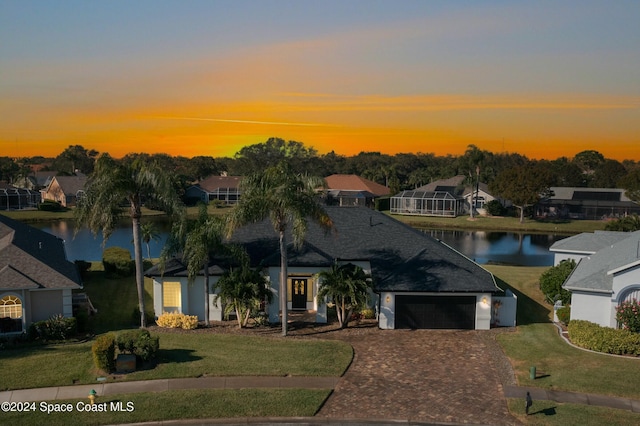 view of front of property with a garage, a water view, and a yard