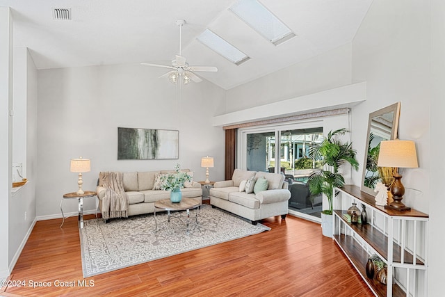 living room with a skylight, high vaulted ceiling, hardwood / wood-style flooring, and ceiling fan