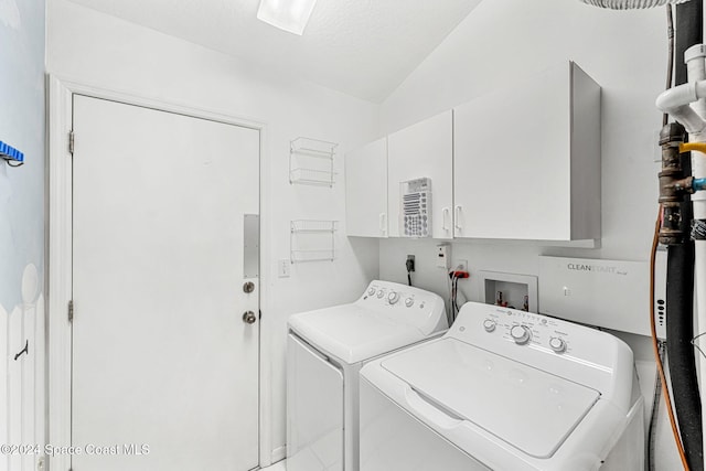 clothes washing area with cabinets, independent washer and dryer, and a textured ceiling