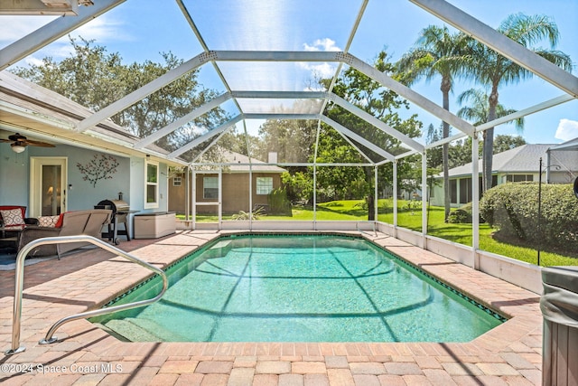 view of swimming pool featuring glass enclosure, a patio area, area for grilling, and ceiling fan