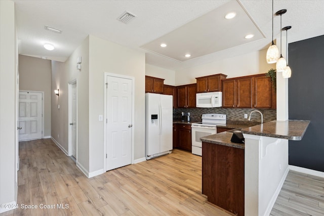 kitchen with kitchen peninsula, decorative backsplash, white appliances, sink, and light hardwood / wood-style floors