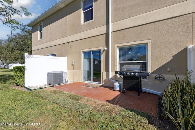 rear view of property with a lawn, central AC, and a patio