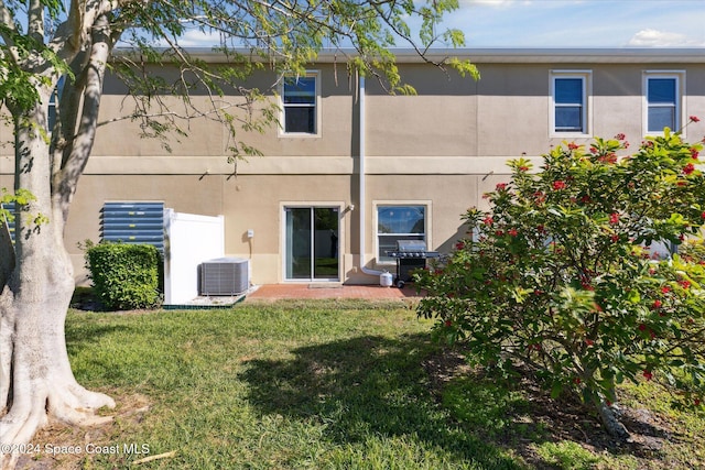 back of property featuring cooling unit and a yard