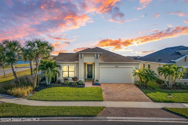 view of front of home featuring stucco siding, decorative driveway, a garage, and a front yard