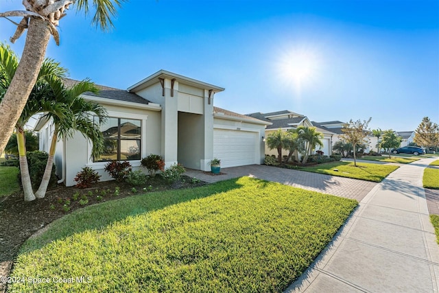 view of front of property featuring a front yard, roof with shingles, stucco siding, decorative driveway, and an attached garage