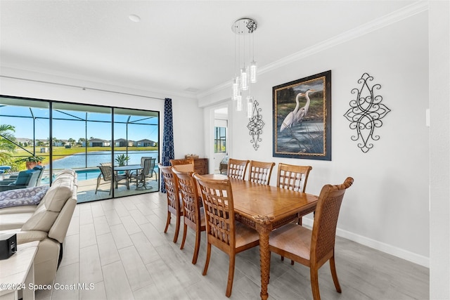 dining space with light wood finished floors, baseboards, a water view, ornamental molding, and a sunroom