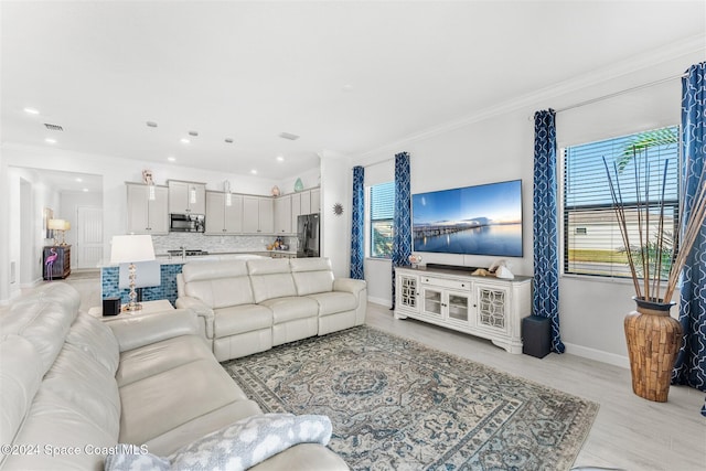 living area with light wood finished floors, visible vents, baseboards, ornamental molding, and recessed lighting