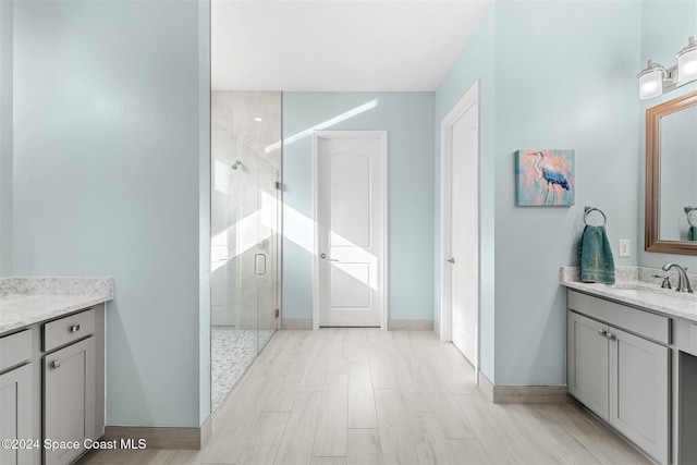 bathroom with a shower stall, vanity, baseboards, and wood finished floors