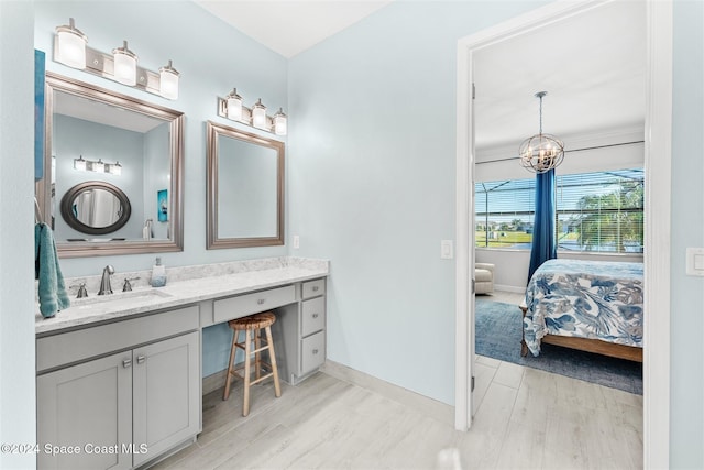 bathroom with baseboards, an inviting chandelier, wood finished floors, and vanity