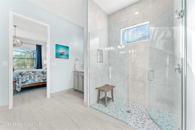 ensuite bathroom featuring a notable chandelier, connected bathroom, a shower stall, baseboards, and vanity