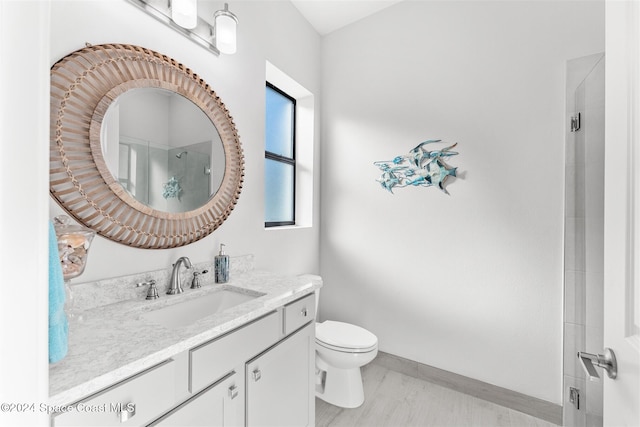 bathroom with toilet, an enclosed shower, vanity, and baseboards