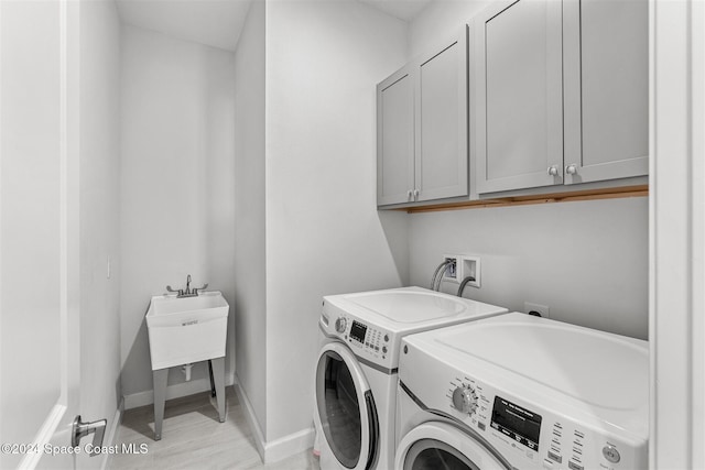 laundry room featuring light wood-style floors, baseboards, cabinet space, and separate washer and dryer