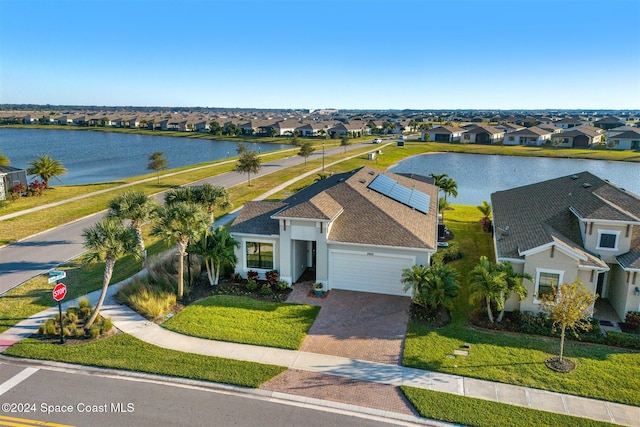 exterior space featuring a water view, decorative driveway, a residential view, a front yard, and a garage