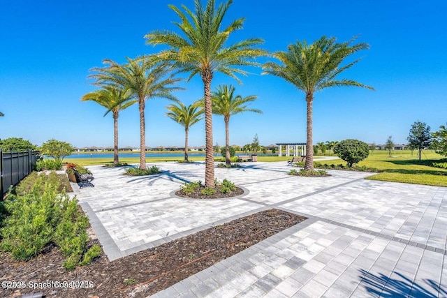 exterior space with decorative driveway, a water view, and fence