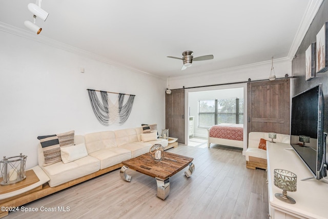 living room with a barn door, ornamental molding, and hardwood / wood-style flooring