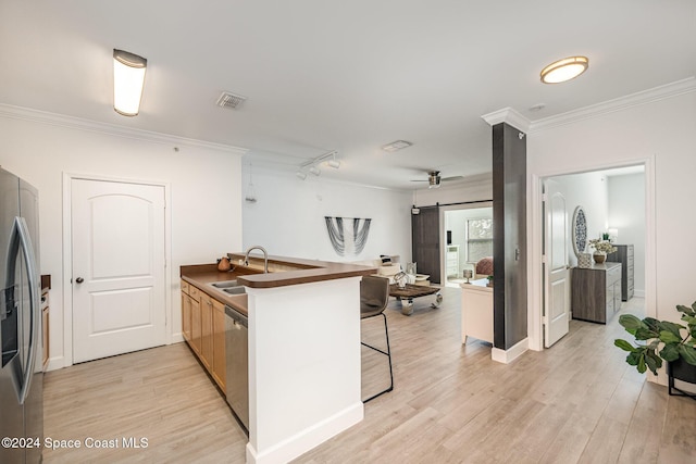 kitchen with a kitchen breakfast bar, sink, light hardwood / wood-style flooring, a barn door, and stainless steel appliances