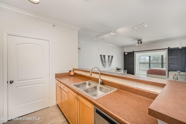 kitchen featuring sink, dishwasher, a barn door, light hardwood / wood-style flooring, and crown molding