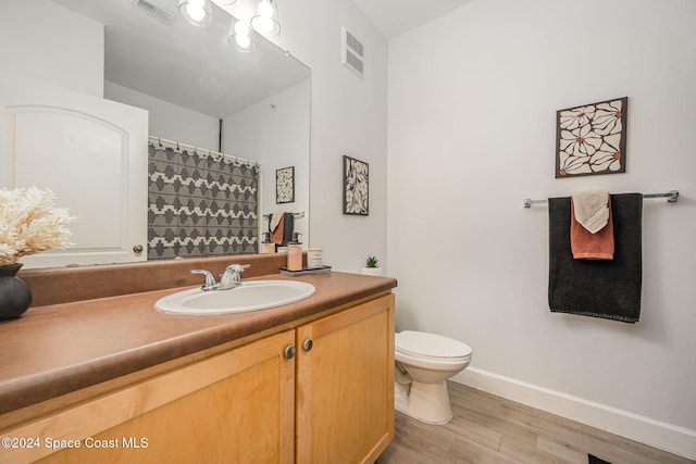 bathroom with wood-type flooring, vanity, and toilet