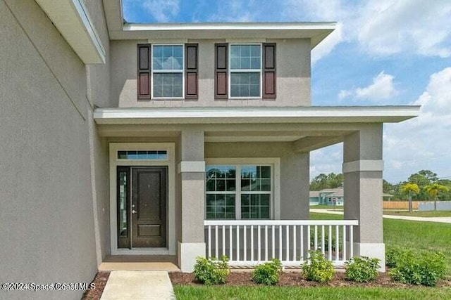 property entrance with covered porch and a lawn