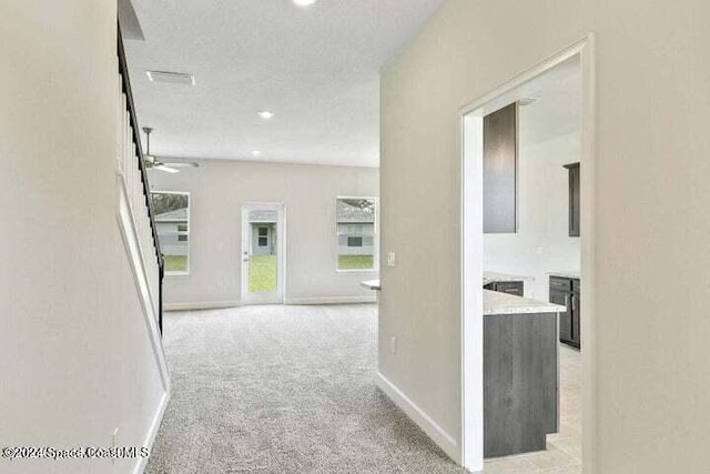 hallway featuring light carpet and a textured ceiling