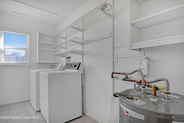 laundry area featuring water heater, washer and clothes dryer, and light tile patterned floors