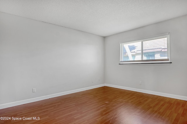 empty room with hardwood / wood-style floors and a textured ceiling