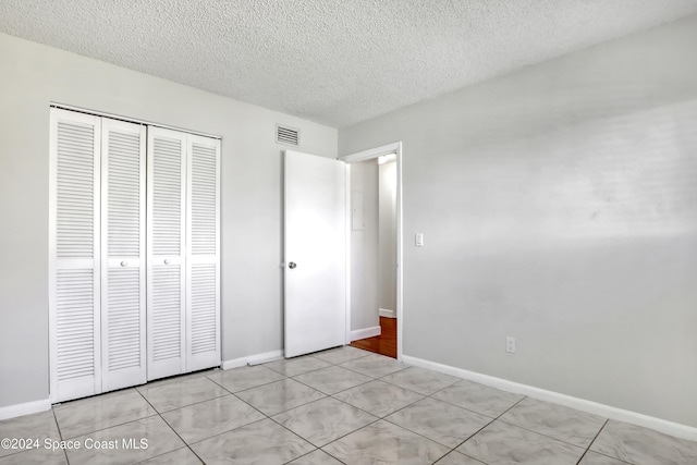 unfurnished bedroom featuring a textured ceiling and a closet