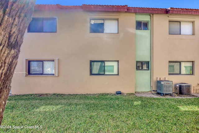 rear view of property with central AC and a lawn