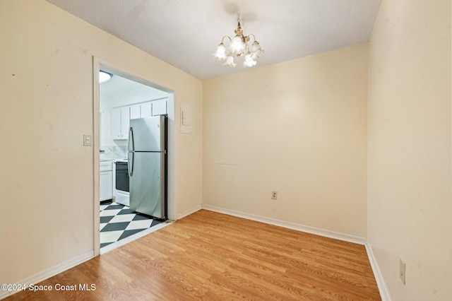 empty room with light wood-type flooring and a notable chandelier