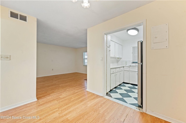 corridor with electric panel and light hardwood / wood-style flooring