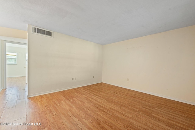 spare room featuring a textured ceiling and light wood-type flooring