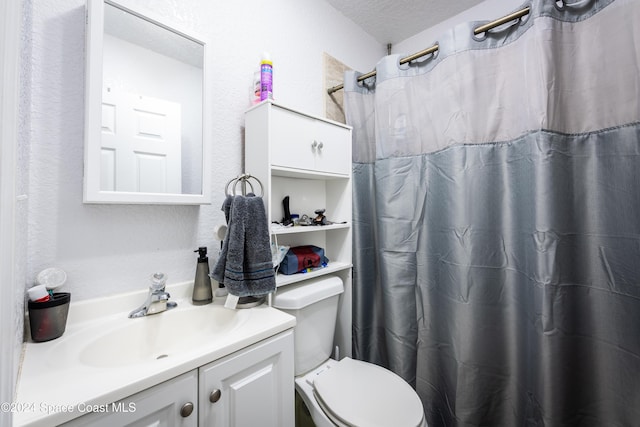 bathroom with vanity, curtained shower, toilet, and a textured ceiling