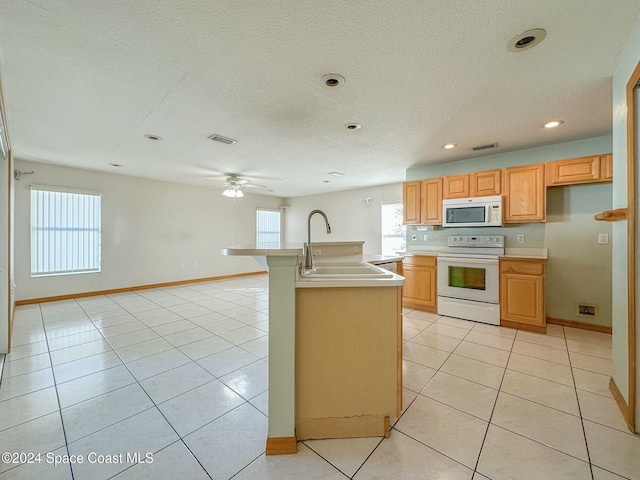 kitchen featuring sink, light tile patterned floors, a healthy amount of sunlight, and white appliances