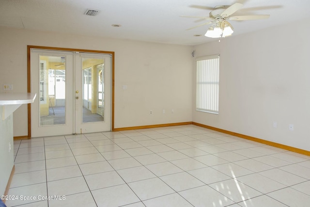 tiled spare room with plenty of natural light, ceiling fan, and french doors