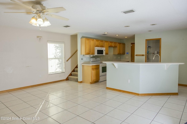 kitchen featuring white appliances, a kitchen island with sink, sink, ceiling fan, and light tile patterned flooring