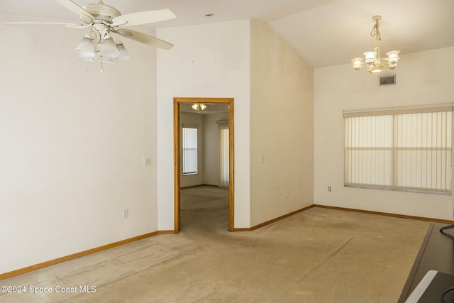 carpeted empty room with ceiling fan with notable chandelier and lofted ceiling