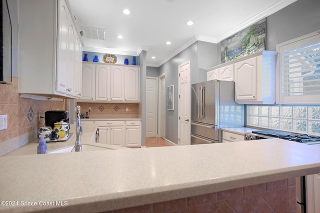 kitchen featuring stainless steel refrigerator, white cabinetry, sink, backsplash, and crown molding