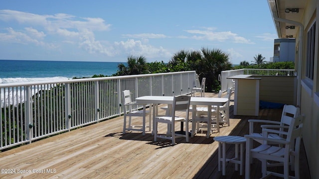 wooden terrace featuring a water view and a view of the beach