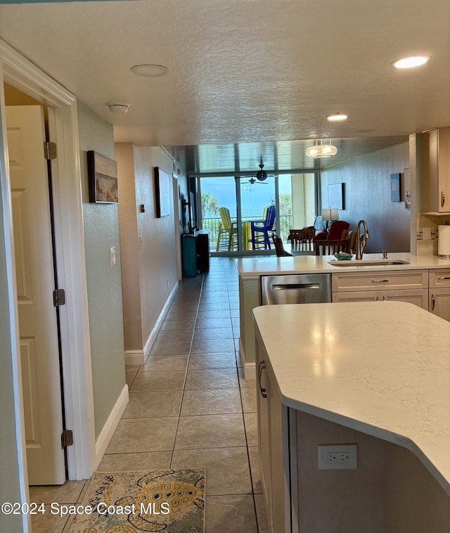 kitchen featuring sink, stainless steel dishwasher, light tile patterned floors, a textured ceiling, and a kitchen island