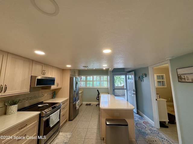 kitchen featuring light brown cabinetry, backsplash, a textured ceiling, stainless steel appliances, and light tile patterned flooring