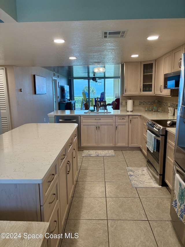 kitchen with a center island, light tile patterned flooring, stainless steel appliances, and sink