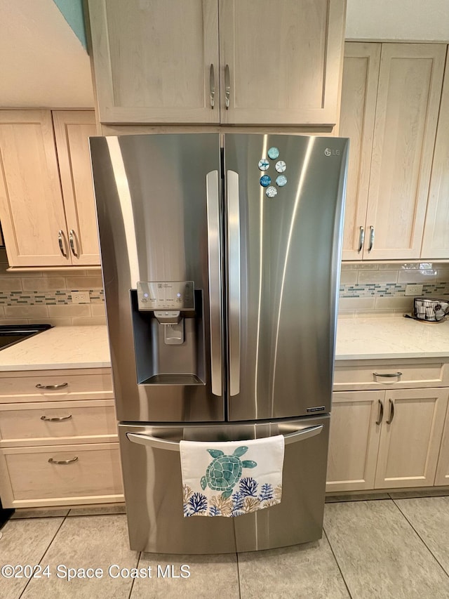 kitchen with stainless steel refrigerator with ice dispenser, backsplash, light stone counters, and light tile patterned flooring