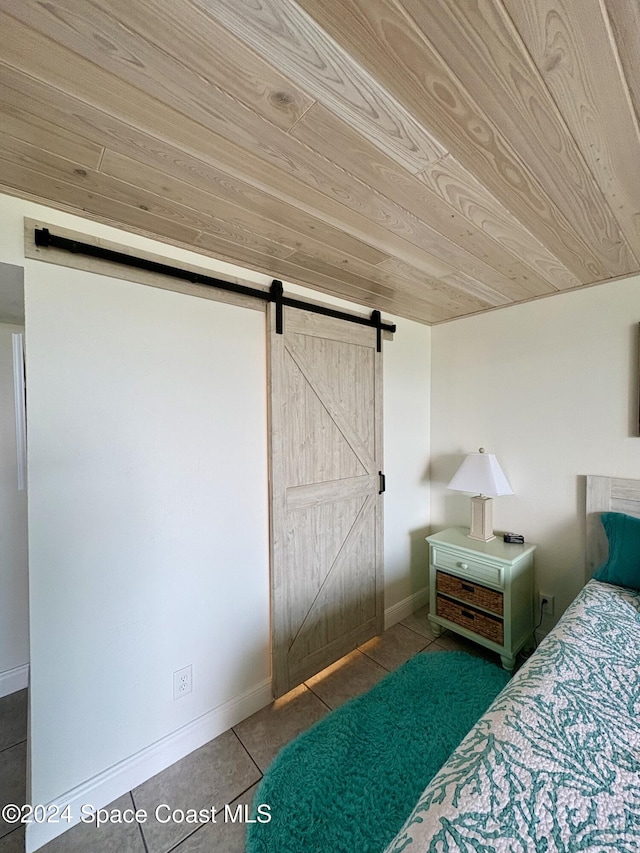 unfurnished bedroom featuring tile patterned flooring, a barn door, and wood ceiling