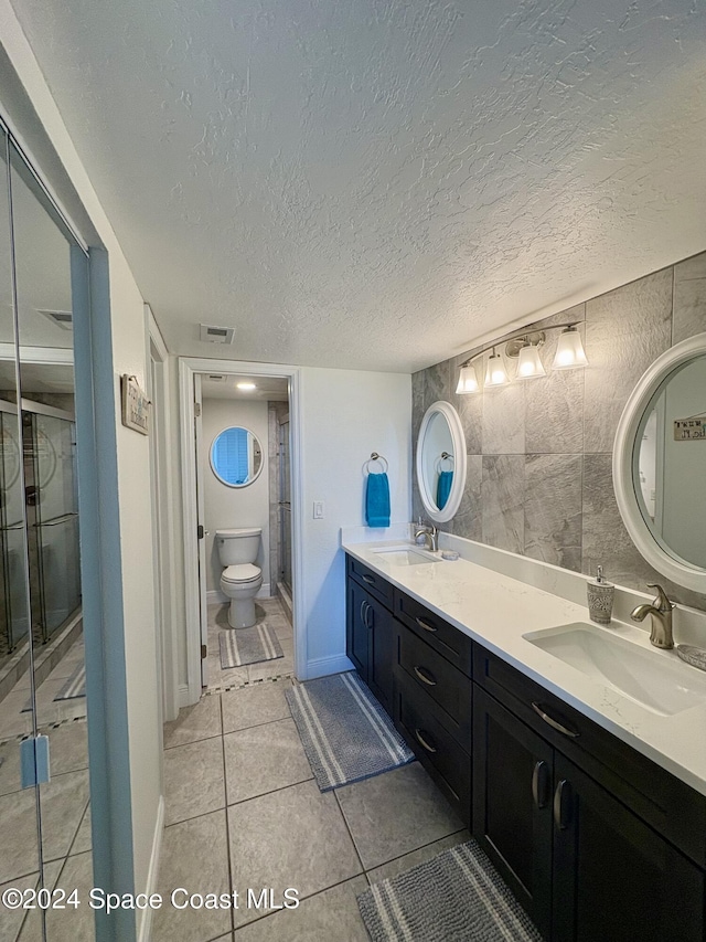 bathroom featuring tile patterned flooring, an enclosed shower, a textured ceiling, toilet, and vanity