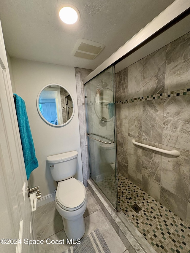 bathroom with a shower with door, a textured ceiling, and toilet