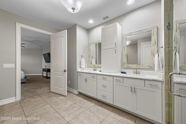 bathroom featuring vanity, a shower with door, tile patterned flooring, ceiling fan, and a textured ceiling